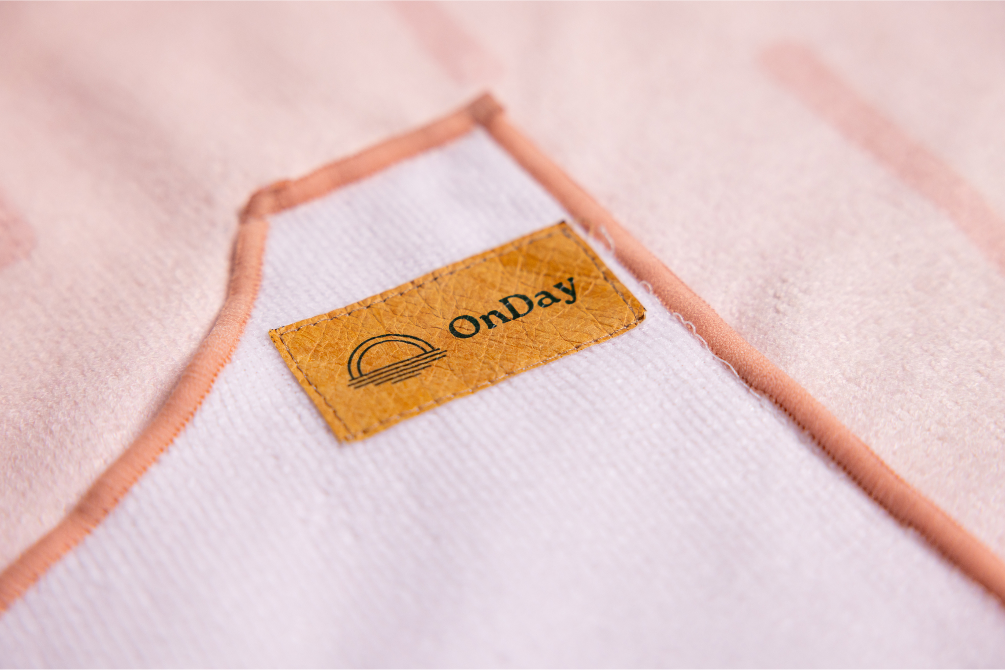 Fabric close up of towel poncho, pink with lines and pockets.